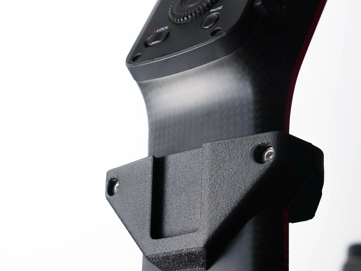 Close-up of a black carbon-fiber-textured camera gimbal handlebar mount with a matte black bracket and mounting screws, set against a clean white background.